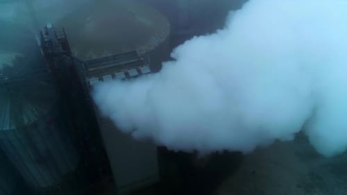 High premises on the territory of grain elevator plant with pipes producing thick smoke.