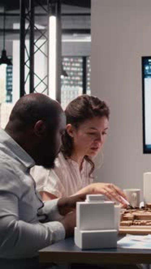 Vertical Video Real Estate Professionals Engage in Meeting to Review Blueprints and 3D Models