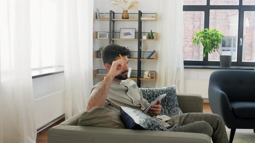 Man Sitting on Couch Writing in a Notebook