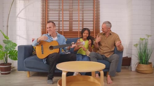 Family Plays Guitar Together on Couch at Home