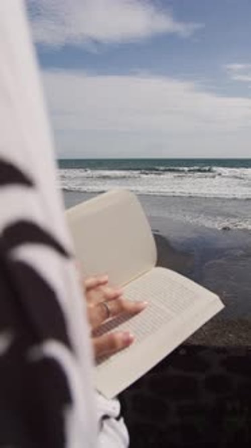 Buch in den Händen eines Mädchens auf dem Hintergrund des Ozeans Vertikales Video