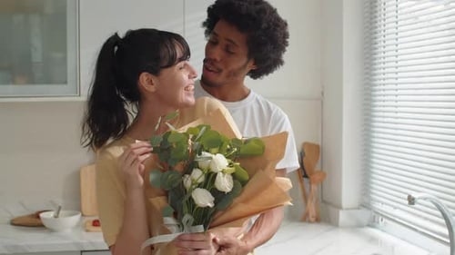 Loving Couple Kissing with Flowers in Kitchen