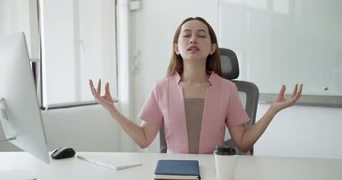 Young Woman Meditating at Office Desk