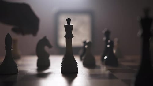 Ein Mann bewegt Schachfiguren auf einem Schachbrett in einem schwach beleuchteten Raum