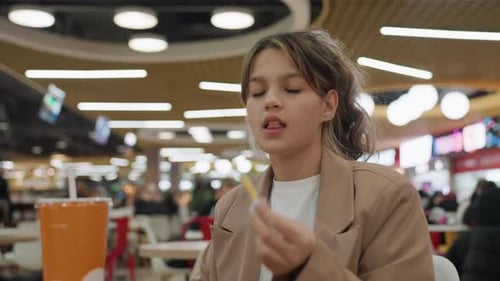 Teenage Girl Eating French Fries at Food Court