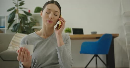 Woman Talking on Phone and Drinking Coffee at Home