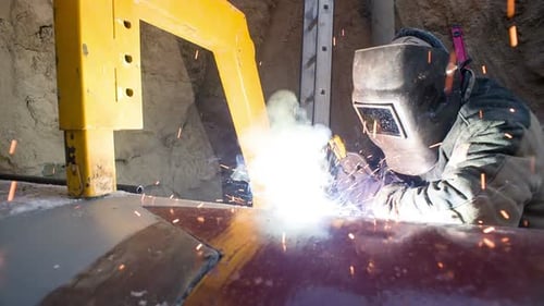 Der Konstrukteur schweißt Teile im Freien. Installation von Rohrleitungen unter der Erde im Winter