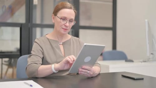 Old Businesswoman Doing Video Chat on Tablet in Office