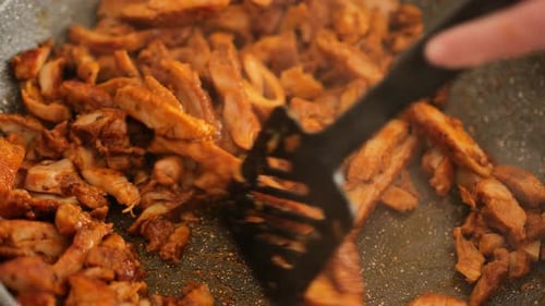 Chicken meat pieces in sauce fry in a frying pan with smoke.Cooking process.