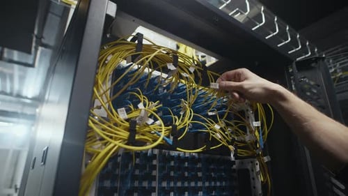 Network Engineer Hand Adjusting Ethernet Cables in Data Center Rack