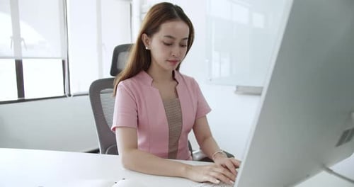 Office work environment featuring young professional woman engaged in task at desk
