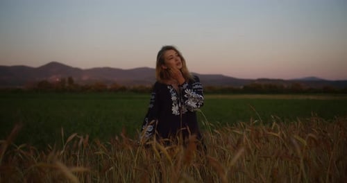 A romantic village girl in an embroidered shirt and in ukrainian vyshyvanka stands in a wheat field