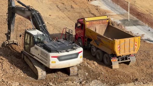 Excavator Loading Soil Into a Dump Truck, Daytime
