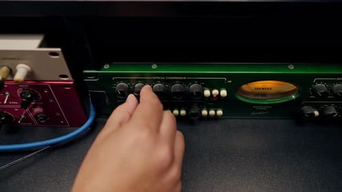 Nahaufnahme der männlichen Hand eines Toningenieurs, der die Einstellungen bei der Aufnahme am Mischpult wechselt