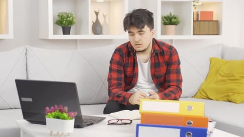 Thoughtful Man Studying at Home with Laptop