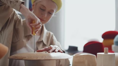 Woman Crafts Stylish Hat in Bright Workshop