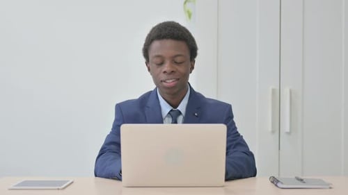 Young Adult in Suit Video Conferencing at Desk