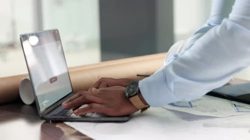 Architektenhände tippen auf einem Laptop, planen und zeichnen Pläne für ein Gebäude