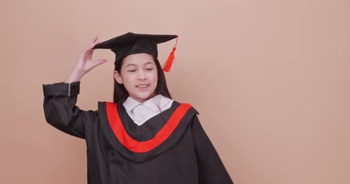 A school girl wearing a graduation gown makes happy gestures and expressions.