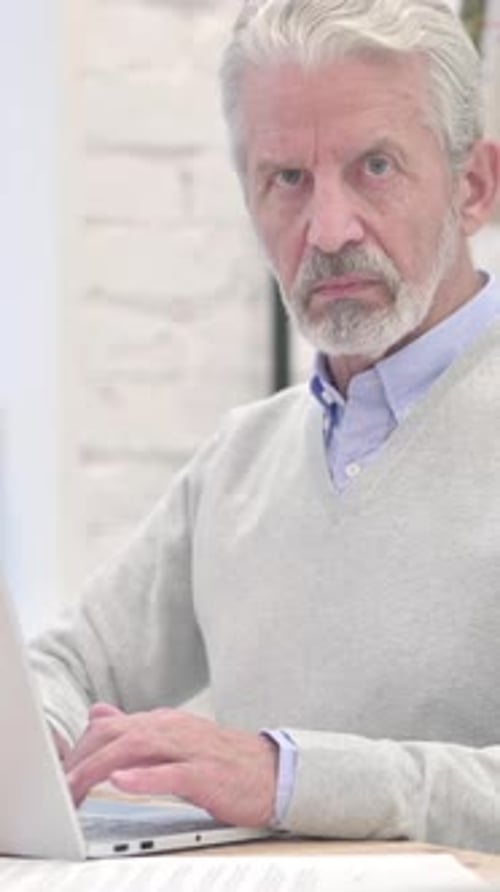 Senior Man Working on Laptop in Bright Office