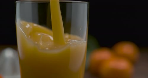 Orange Juice Being Poured into Glass with Ice