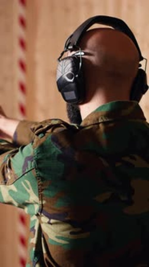 Vidéo verticale Un soldat joyeux s'entraînant avec une arme à feu exulte après avoir touché la cible avec précision