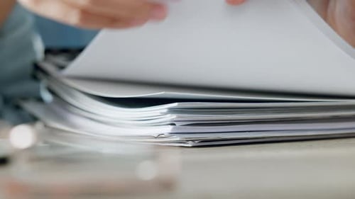 Hands Flipping Through Stack of White Paper