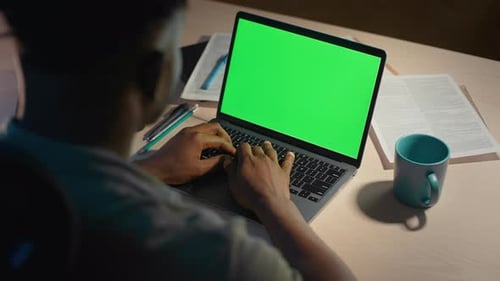 Hardworking Male Typing on Laptop with Blank Green Screen