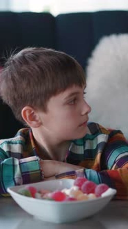 Curious Young Funny Boy Eating Candies When Nobody is Watching His Busy Elder Sister Using