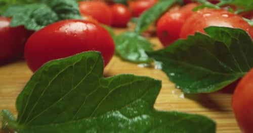 Super macro of a composition of tomatos and basil leaves on a wooden table, the camera goes really