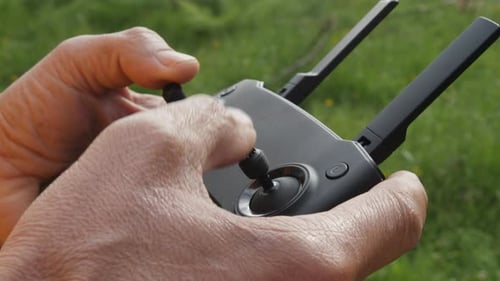 Close-up of hands using a remote control while operating a drone.