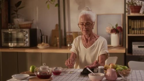 Senior Woman Prepares Pills at Kitchen Table