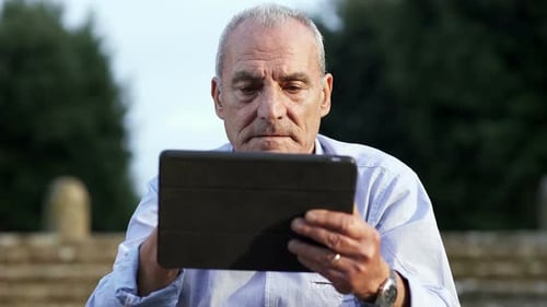 Mature Man Using Tablet Device Outdoors