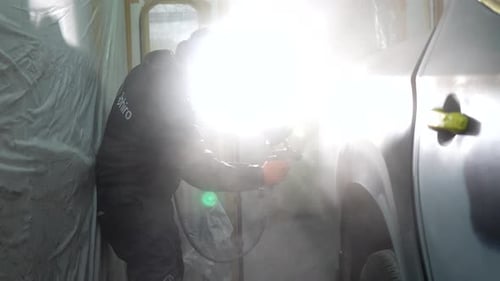 Man Painting Car with Spray Gun Indoors