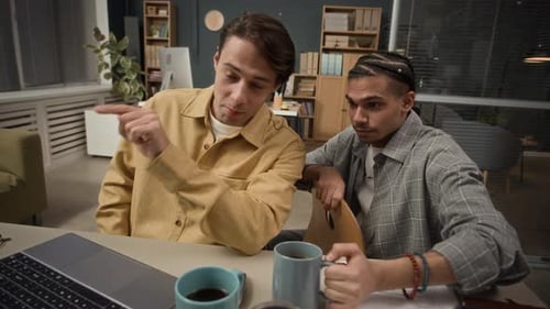 Young Multiethnic Male Coworkers Brainstorming at Desk in Open Space Office