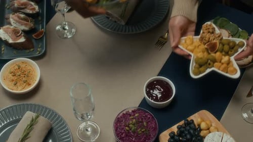 Top View of People Putting Roast Meat and Appetizers on Christmas Dinner Table