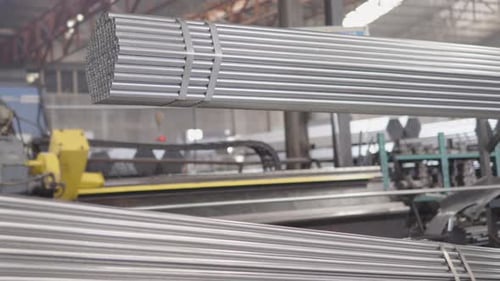 Steel Pipes Undergoing Manufacturing Processes and Being Stacked in Bundles Showcasing Modern