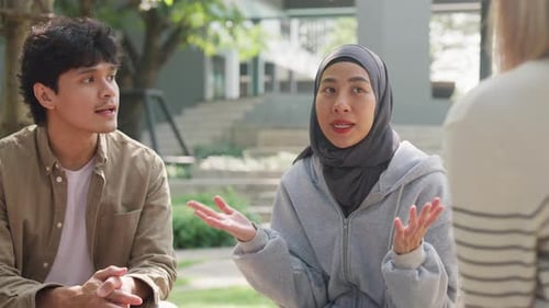 Small Asian group of people sit in a close circle and talk to a therapist in park.