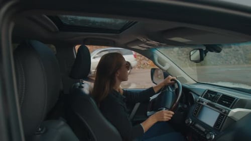Young Woman Steers the Big 4X4 Car on a Bumpy Unpaved Road