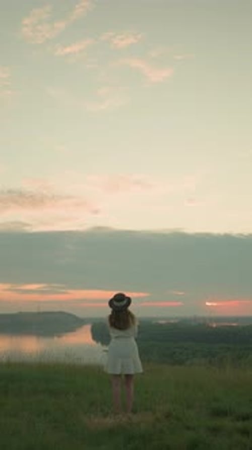 Wife in White Dress Gazing at Tranquil Lake Under Pastel Sky in Grassy Field