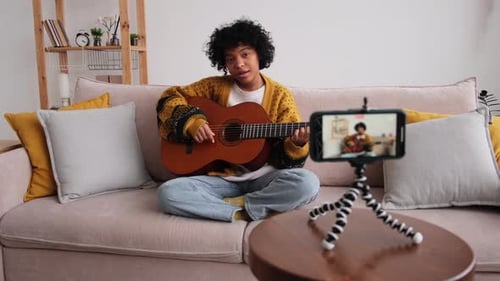 Young Woman Playing Guitar and Singing at Home