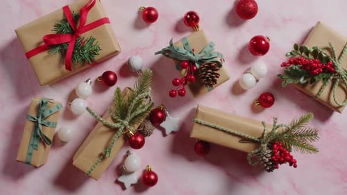 Arranging Christmas Gifts and Ornaments on Pink Marble
