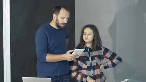 Man and Teen Looking at Tablet Device Indoors