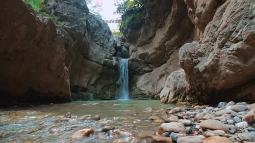 Waterfall flowing between rocky cliffs in peaceful natural landscape