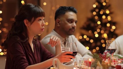 Friends Gather Around Christmas Dinner Table With Wine
