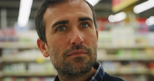 Authentic close up shot of happy young man is choosing food products while shopping for groceries