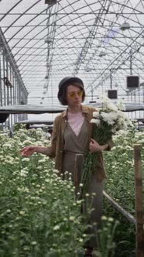 Stylish Woman Holding Flowers in Greenhouse