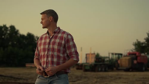Farmer Looking Wheat Field at Golden Summer Sunset. Successful Agrarian Businessman Stand