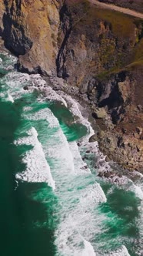 Aguas oceánicas de color aguamarina con olas blancas y espumosas que salpican las rocas.
