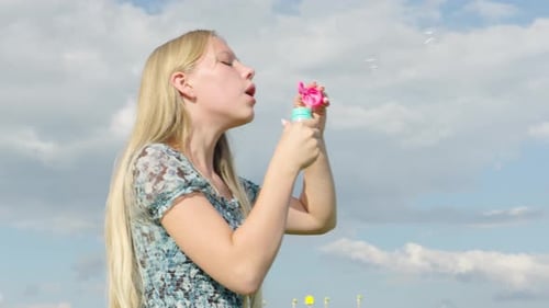 Joyful moments of a girl creating colorful bubbles under a sunny sky